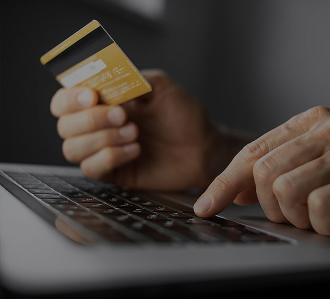 man typing on laptop while holding credit card